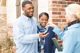 young adult couple receives a house key to their first home from their realtor. 