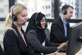 Three customer service representatives talking on heatsets and looking at computers