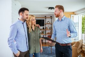 Couple talking to realtor with a clipboard in hand