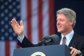 President Bill Clinton giving a speech in front of an American flag, 1995