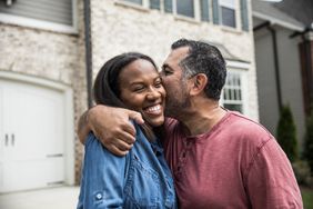 Smiling, embracing couple in front of new home