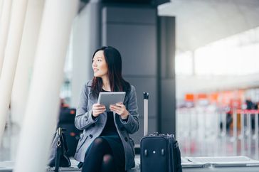 A woman waits for a flight she booked with her Amex Membership Rewards points.