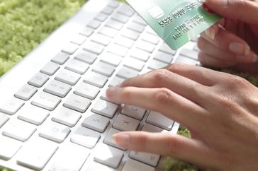 Internet shopping with a person typing on a keyboard with one hand and holding a credit card in the other