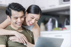 A young couple smile as they look at a computer screen together