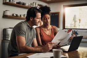 A couple at kitchen table with paperwork and laptop