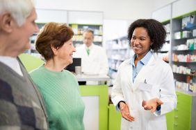 African American pharmacist communicating with senior couple in a pharmacy.