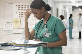 Concerned female nurse looking at chart in hospital
