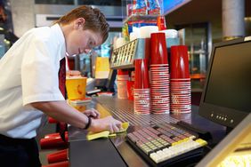 Teenage boy (14-16) cleaning refreshments counter in cinema