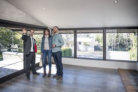A couple tours an empty home with a real estate agent.