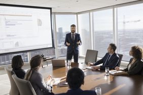 Businessman leading presentation at projection screen in conference room meeting