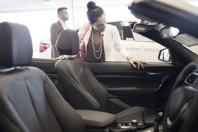 Woman looking into a convertible at a car dealership