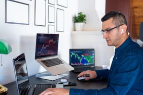 Man analyzing market charts on laptop computer screen at home office 