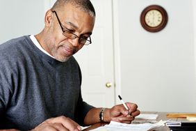 Man using calculator at home table to figure average daily balance finance charges