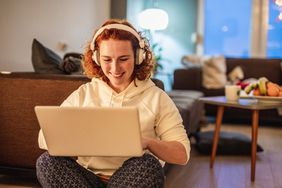 Woman sitting with laptop in lap wearing headphones