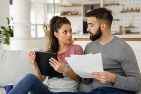 Couple going over their finances together at home using digital tablet