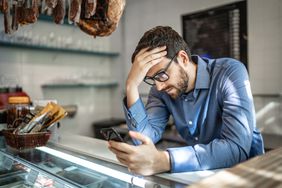 man in blue shirt on iphone in a store looking worried