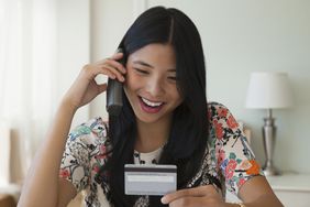 A woman holds a credit card while talking on the phone