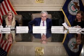 Fed chairman Jerome Powell sits at a table flanked by colleagues.