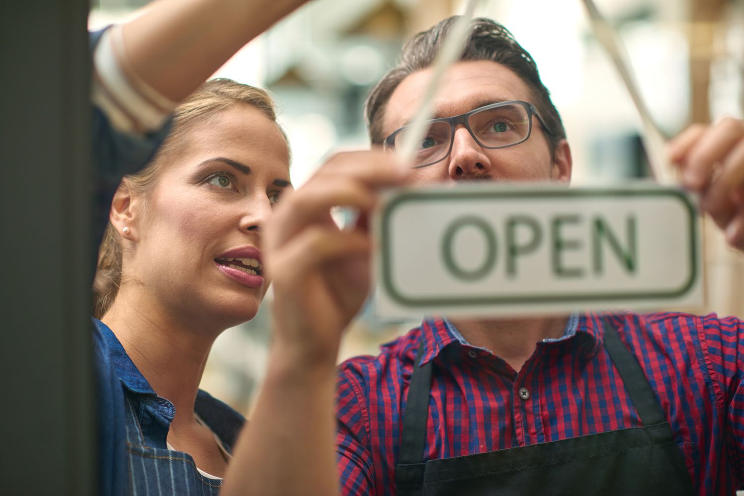 a businessman and woman hanging up an open sign