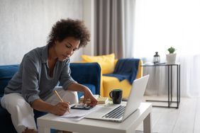Woman doing taxes at home with a smartphone and laptop