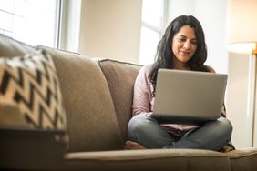 Woman sitting on couch with laptop open