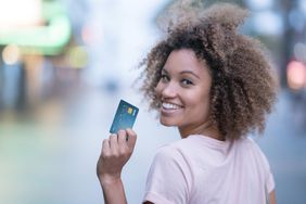 Happy woman holding a credit card and smiling