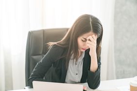 Stressed worker with her head in her hands at her office desk experiencing anxiety