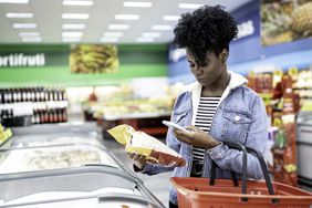 Woman looking at smartphone while grocery shopping