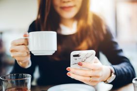 Woman holds iphone and cup of coffee