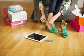 woman trying on green high heels with tablet and credit card
