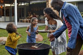 A family enjoys a barbecue in their yard.