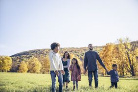 Young family of five walking through meadow in Autumn