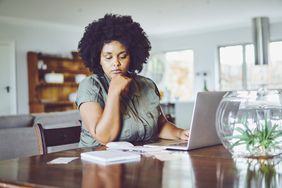 Woman looking concerned while paying bills from home