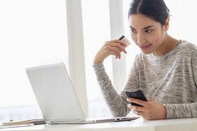 Woman with credit card, phone and laptop