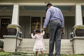 Father and daughter walking up steps to house