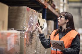Warehouse worker in orange vest checking shipment box