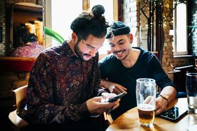 Two men drinking together and looking at a smartphone at a craft-beer bar