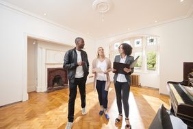A real estate agent shows a couple around a refurbished period home