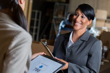 Businesswoman with a good credit score talks with a customer in a warehouse