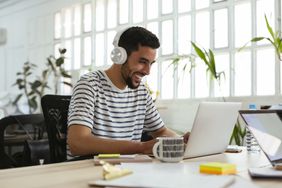  Laughing man wearing headphones using laptop
