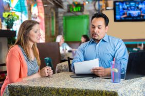 Restaurant manager reading resume and interviewing young woman for job