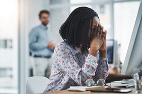 Woman looking stressed at her desk in the office