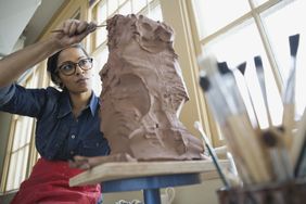 Woman using sculpting tools on a sculpture as she thinks about turning it into a business