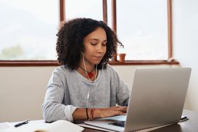 young girl working on computer with headphones in