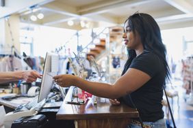 Young woman paying cashier in clothing store