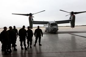 Marines from the 3rd Marine Aircraft wing walk by a V-22 Osprey
