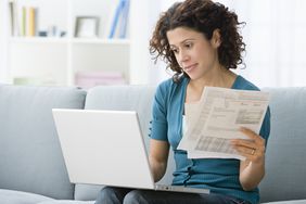 Woman reviewing paper statements and online records