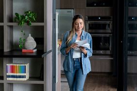 woman walking at her apartment while opening letters 