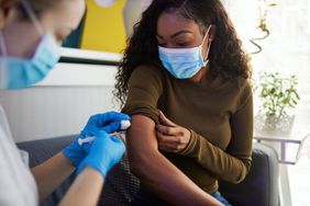 Woman with sleeve rolled up gets a vaccination from a nurse