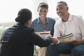 Black couple talking to businesswoman in their home